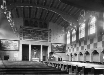 Fotografische Darstellung der Innenansicht mit Sitzbänken im Vordergrund, der Chornische im Hintergrund und der Kirchendecke.