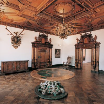 The former living room of the Kiechelhaus with a carved and decorated wooden table in the middle.