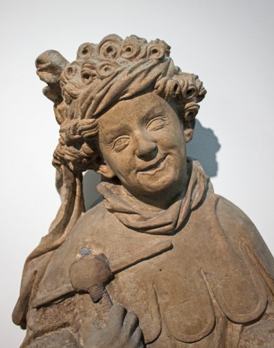 Portrait of a young man with curled hair and mischievous smile.