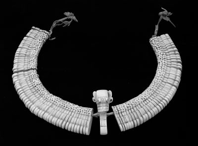 Headband from seashell with a central amulet depicting a face with revealed teeth and huge eyes.