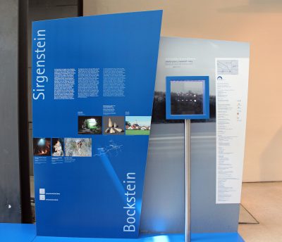Ausstellungsansicht mit einer Vitrine, in der mehrere winzige Schmuckstücke aus Mammutelfenbein ausgestellt sind.