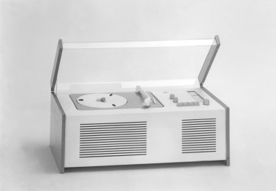 Radio-Phonogerät in rechteckiger Form mit nach oben verlagerten Bedienelementen und Plexiglasdeckel.