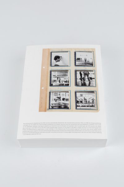 Farbfoto: Ein weißes Buch liegt auf einem hellgrauen Untergrund