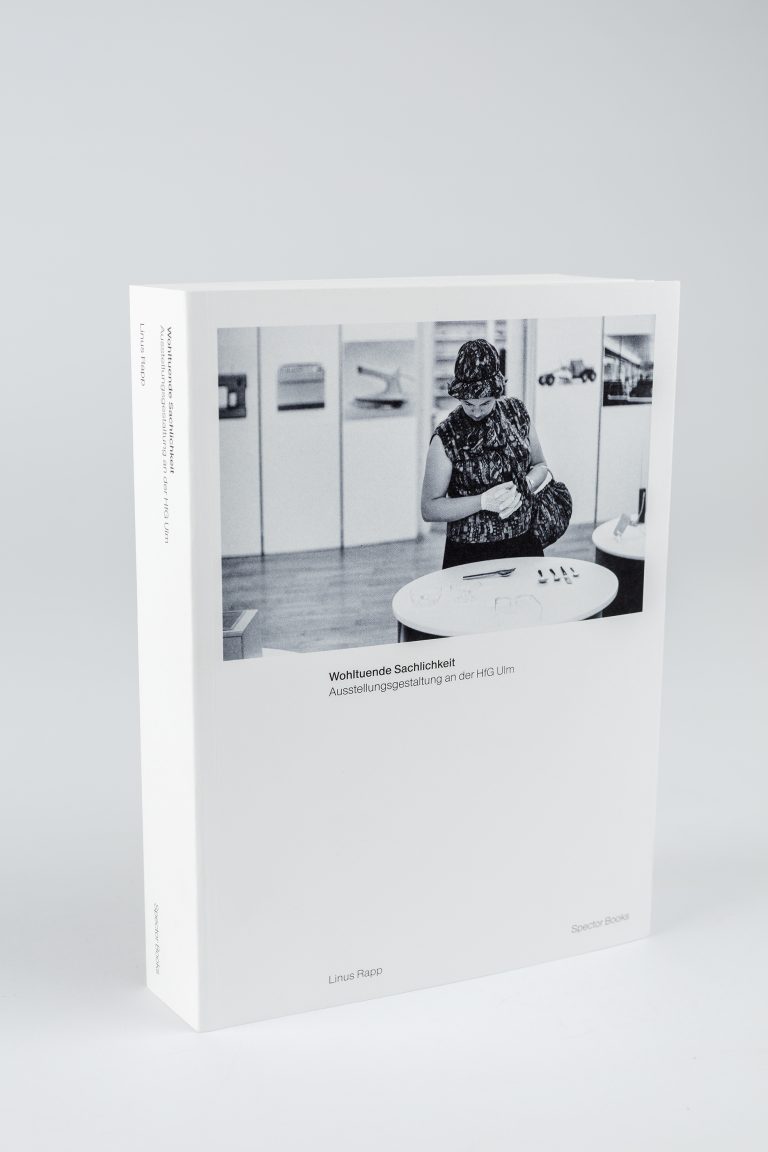Farbfoto: Ein weißes Buch steht auf einem hellgrauen Untergrund