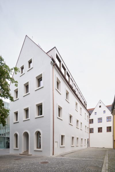 Farbfoto: Ein hohes weiß gestrichenes Haus mit spitzem Giebel